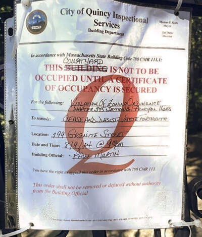 A cease and desist notice was posted on the gate of a Lutheran Church in Quincy after the church allowed Haitian migrants to sleep in tents on its grounds. (Simón Rios/WBUR)