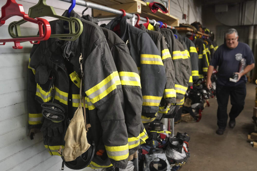 A Brockton firefighter walks past protective gear at Station 1. (Steven Senne/AP)