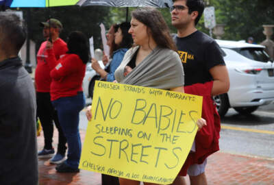 A woman, whose baby is swaddled to her chest, joins a protest against new restrictions to be made to family emergency shelter. (Sam Drysdale/SHNS)